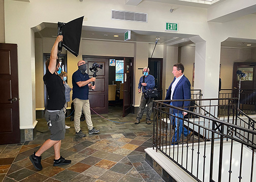 A film crew videotapes a man walking up a staircase at the CenCal Health Office.