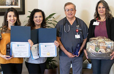 A doctor stands with three healthcare professionals with awards.