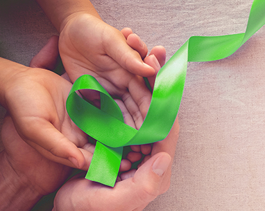 A pair of human hands holding a green ribbon.