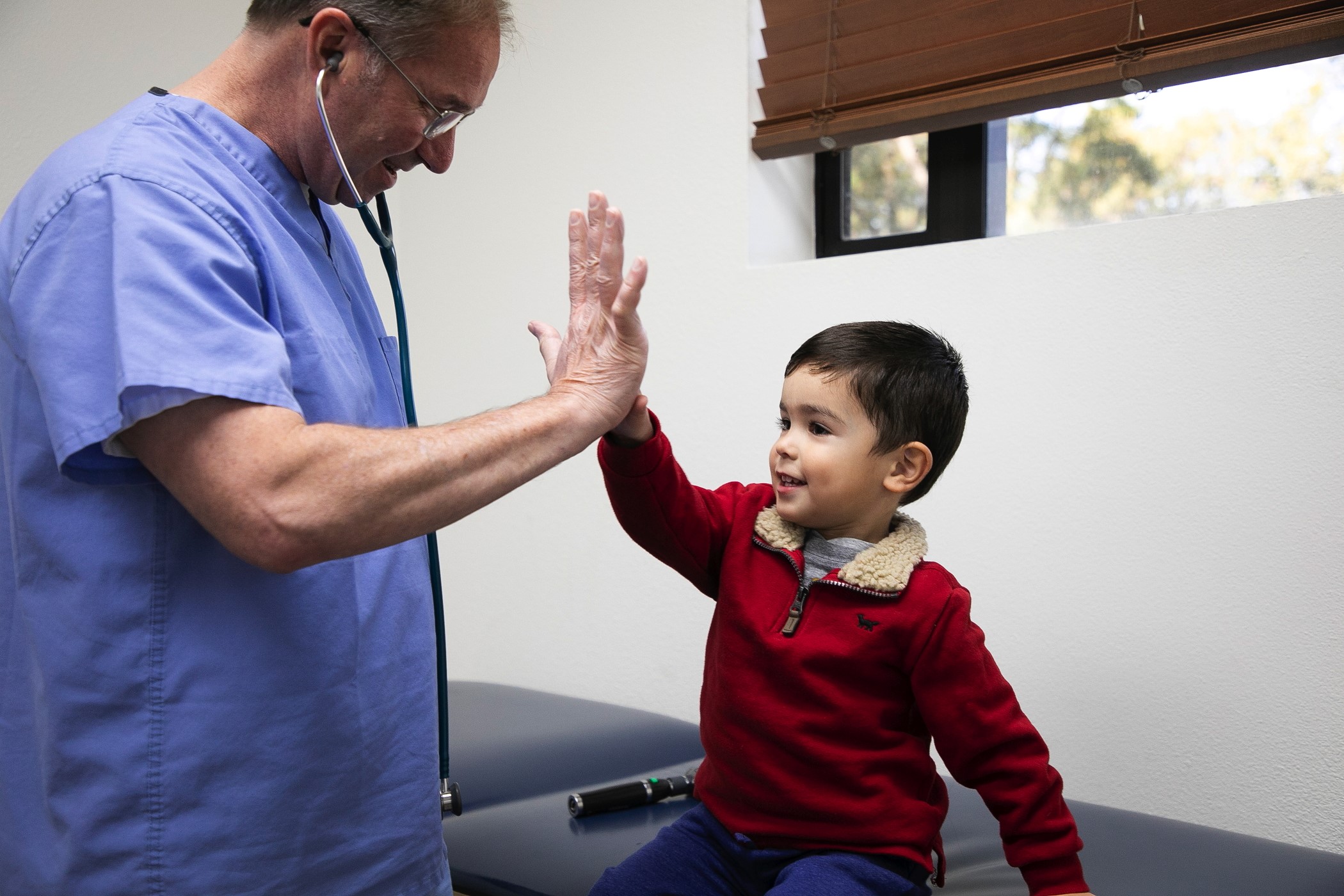A Doctor giving a child a high five in the doctor's office.